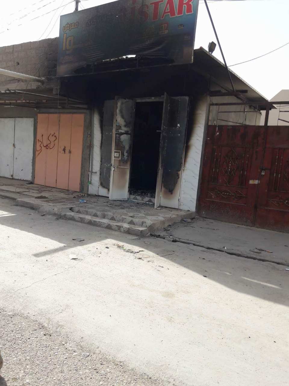 A shop that belongs to Kurds burned by Hashd al-Shaabi militias, while next door shop (R) a writen sign shows it belongs to Turkmen.